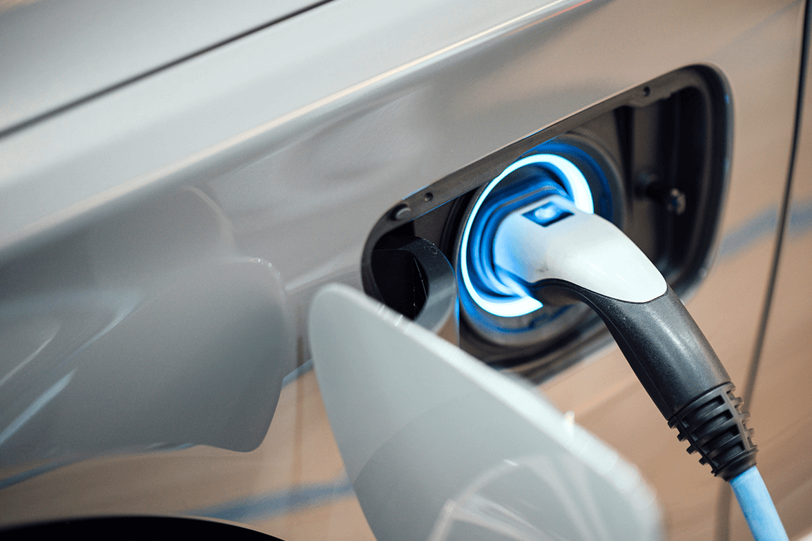 close-up of the charging plug connected to the vehicle's charging port with a glowing blue light.